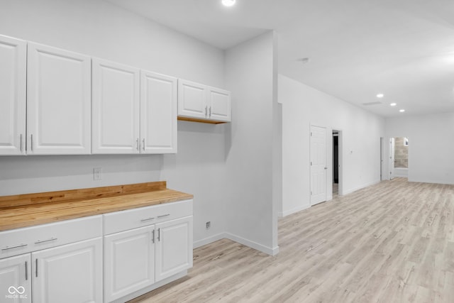 kitchen featuring white cabinets, light wood-type flooring, and wood counters