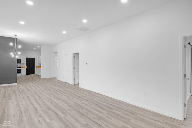 unfurnished living room featuring a notable chandelier and light hardwood / wood-style flooring