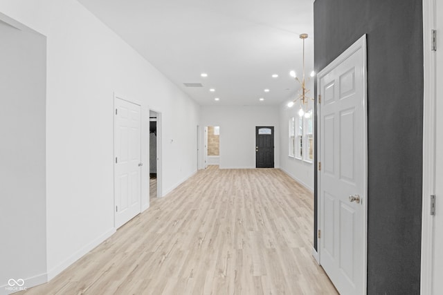 hallway with a chandelier and light wood-type flooring