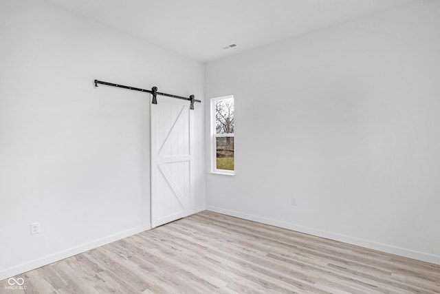 spare room with light wood-type flooring and a barn door