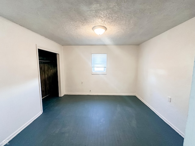 unfurnished room with dark hardwood / wood-style flooring and a textured ceiling