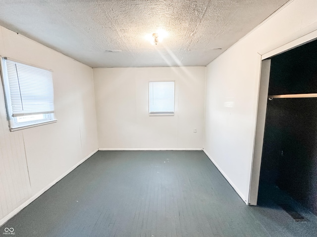 unfurnished bedroom featuring a closet, a textured ceiling, and multiple windows