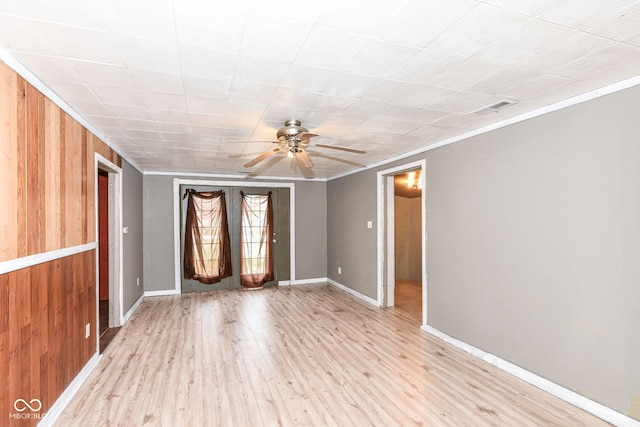 unfurnished room with light hardwood / wood-style flooring, ceiling fan, wooden walls, and crown molding