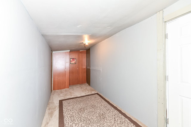 hallway with light carpet and vaulted ceiling