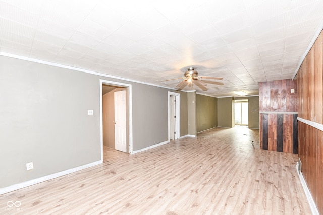 spare room featuring wood walls, ceiling fan, light hardwood / wood-style floors, and ornamental molding