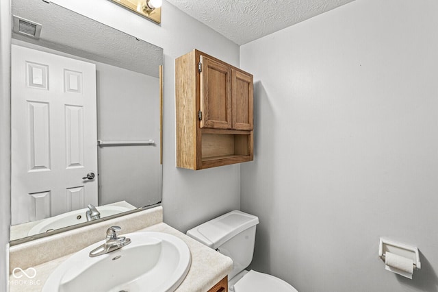 bathroom featuring vanity, a textured ceiling, and toilet