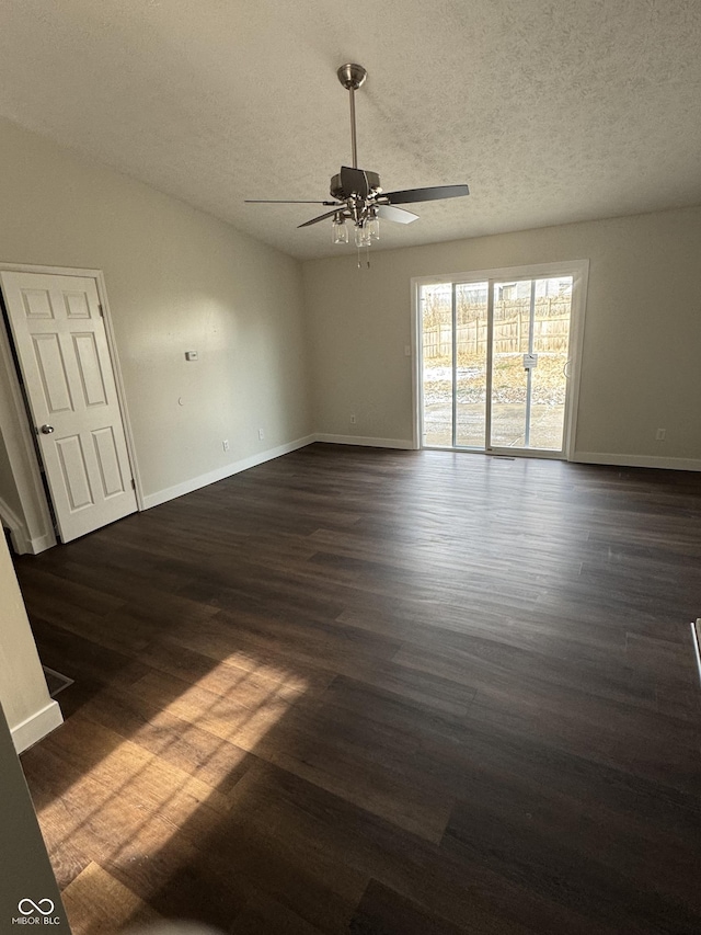 empty room with ceiling fan, dark hardwood / wood-style flooring, and a textured ceiling