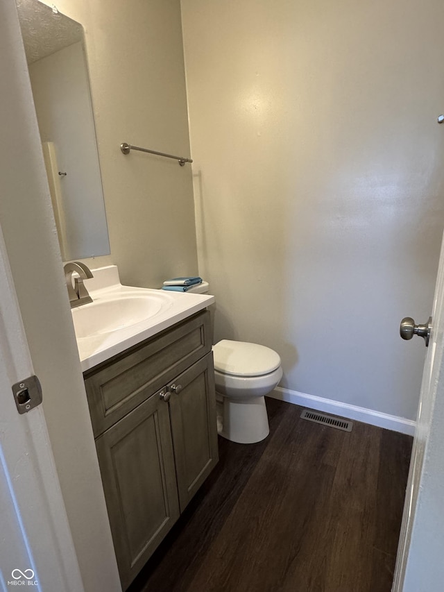 bathroom with wood-type flooring, vanity, and toilet