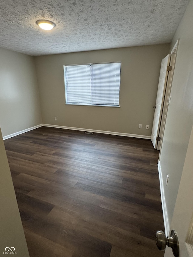 spare room with a textured ceiling and dark wood-type flooring