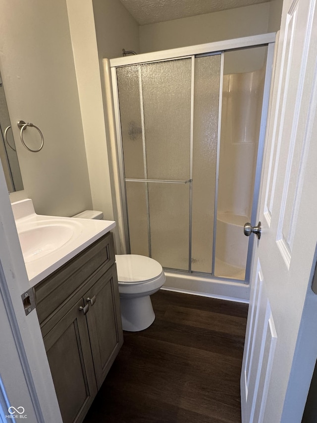 bathroom featuring walk in shower, vanity, a textured ceiling, hardwood / wood-style floors, and toilet