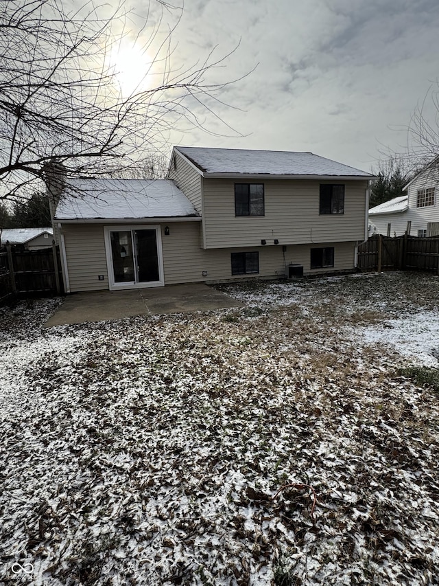 snow covered back of property with central AC unit and a patio area