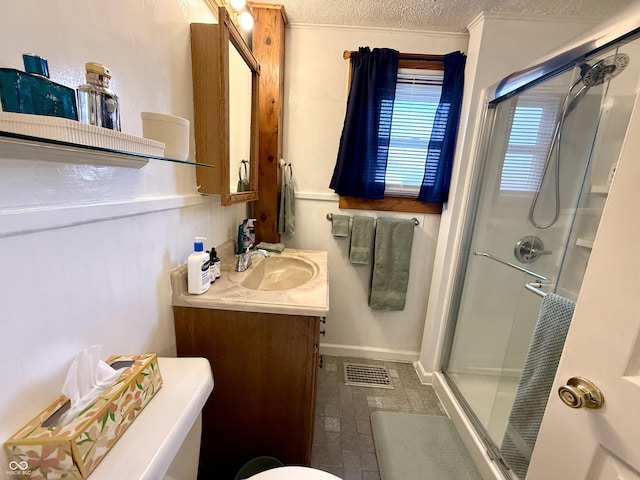 bathroom with a shower with door, vanity, a textured ceiling, and toilet