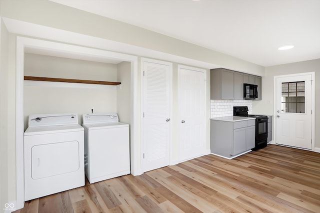 clothes washing area with washing machine and clothes dryer and light hardwood / wood-style floors