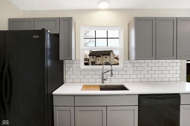 kitchen featuring gray cabinetry, decorative backsplash, sink, and black appliances