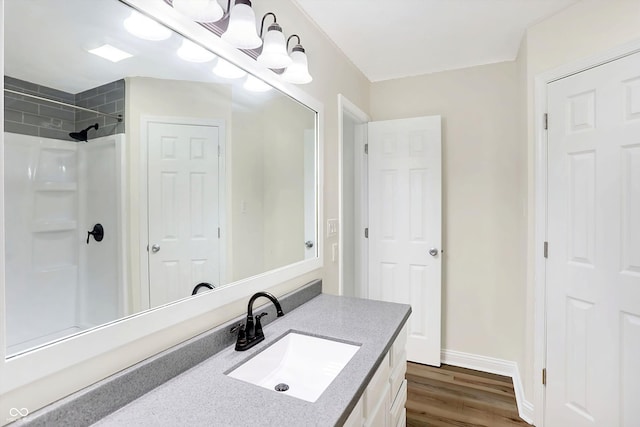 bathroom with tiled shower, vanity, and hardwood / wood-style flooring