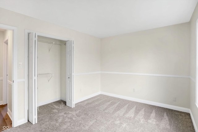 unfurnished bedroom with a closet and light colored carpet