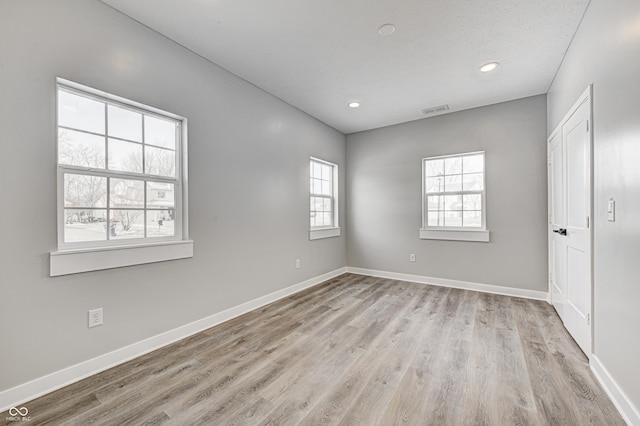 empty room with a wealth of natural light and light wood-type flooring