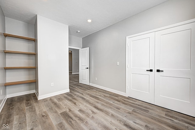 unfurnished bedroom featuring a closet, hardwood / wood-style floors, and a textured ceiling