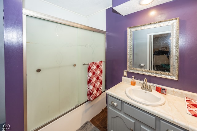 bathroom featuring shower / bath combination with glass door, a textured ceiling, and vanity