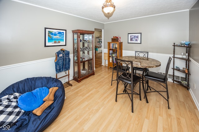 dining area with crown molding, light hardwood / wood-style floors, and a textured ceiling