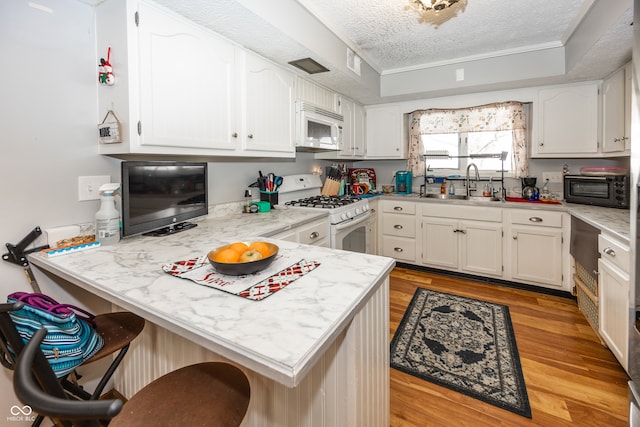 kitchen with sink, light hardwood / wood-style floors, a textured ceiling, white appliances, and white cabinets