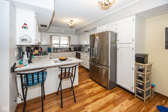 kitchen with white cabinets, stainless steel fridge with ice dispenser, and kitchen peninsula