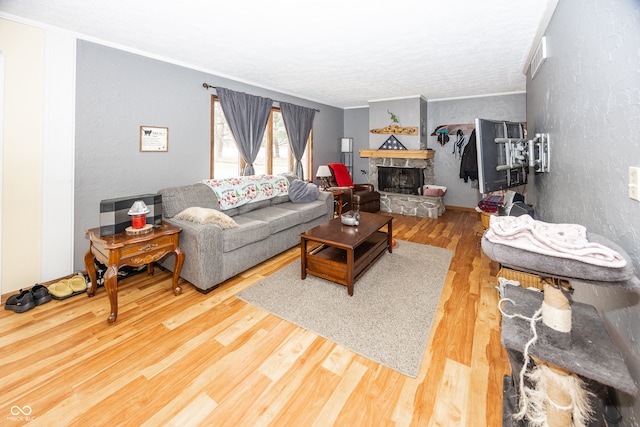 living room featuring crown molding, a fireplace, and wood-type flooring