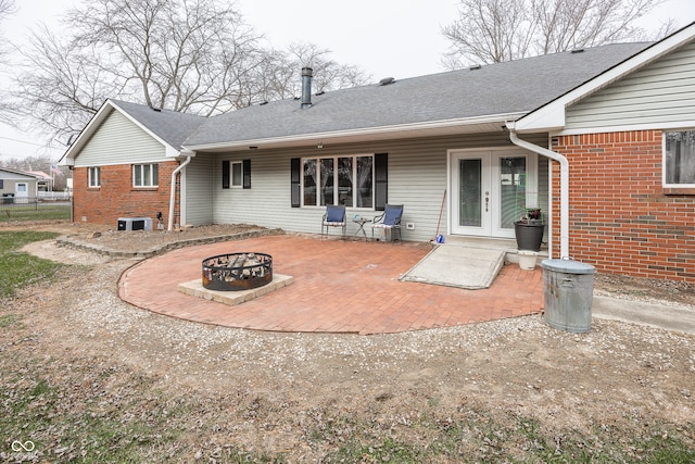 rear view of property with a fire pit, central air condition unit, a patio, and french doors