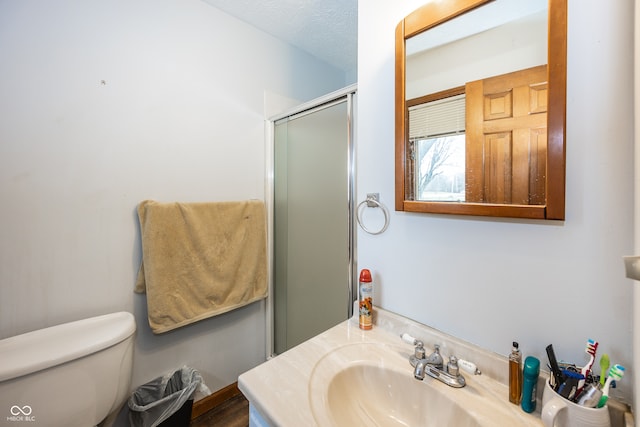 bathroom featuring vanity, a textured ceiling, toilet, and an enclosed shower