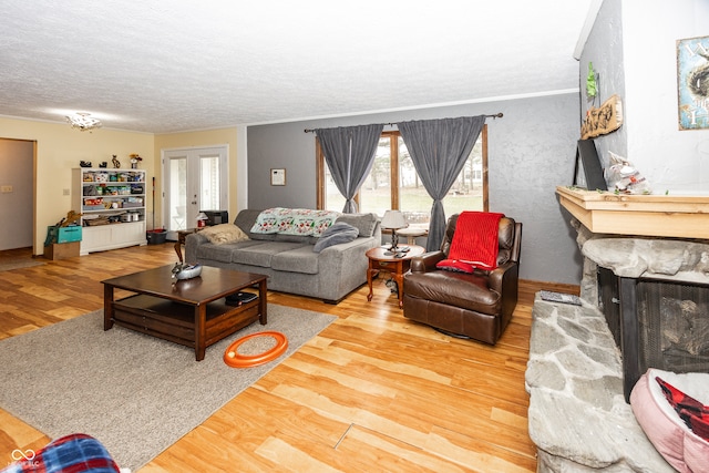 living room with a fireplace, french doors, a textured ceiling, and hardwood / wood-style flooring