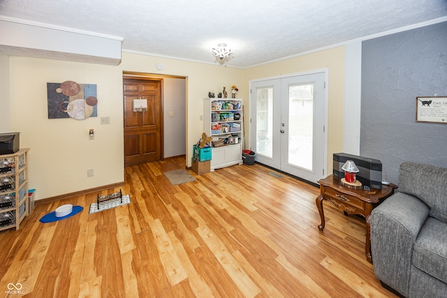 living area with hardwood / wood-style floors, a textured ceiling, crown molding, and french doors