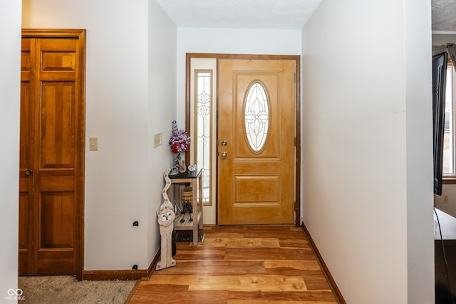 foyer with a textured ceiling and light hardwood / wood-style flooring