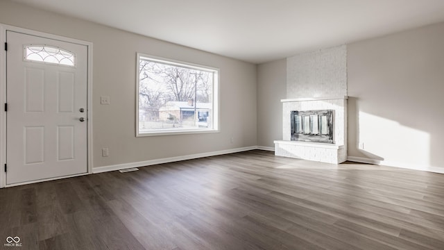 entrance foyer featuring a wealth of natural light, dark hardwood / wood-style flooring, and a brick fireplace