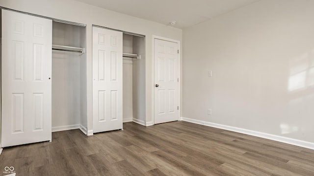 unfurnished bedroom with multiple closets and dark hardwood / wood-style flooring