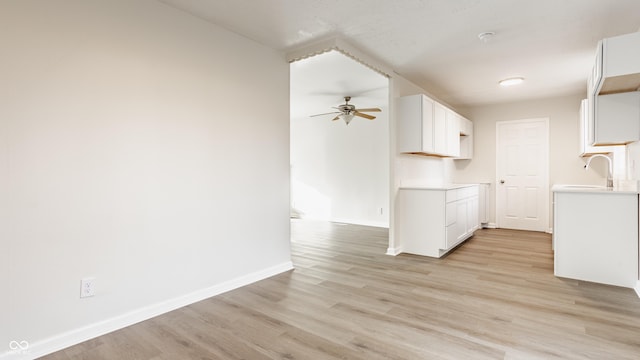 kitchen with white cabinetry, sink, ceiling fan, and light wood-type flooring