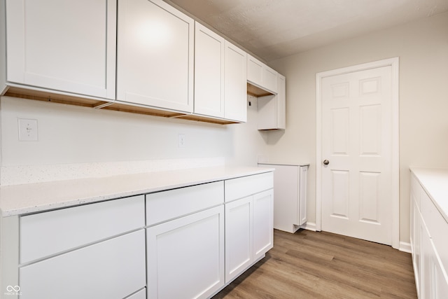 kitchen with white cabinetry and light hardwood / wood-style flooring