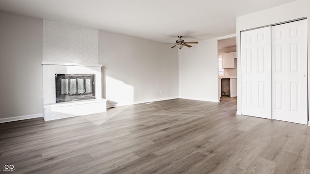 unfurnished living room featuring a fireplace, hardwood / wood-style flooring, and ceiling fan