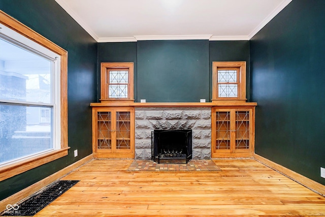 unfurnished living room with a fireplace, wood-type flooring, a wealth of natural light, and crown molding