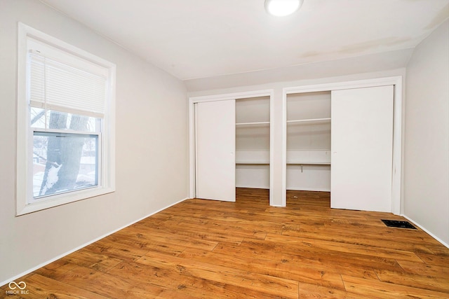 unfurnished bedroom featuring multiple closets and hardwood / wood-style flooring