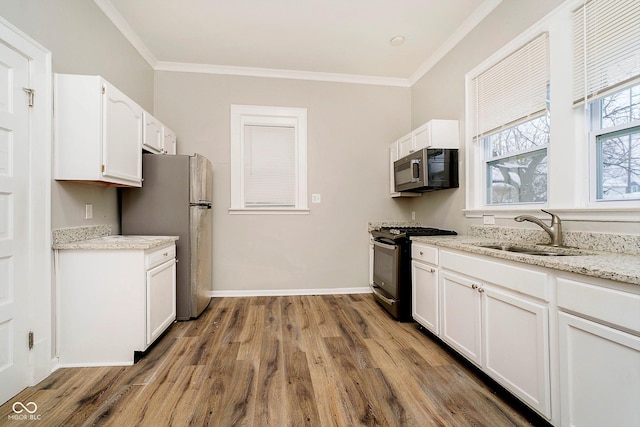 kitchen featuring appliances with stainless steel finishes, ornamental molding, sink, hardwood / wood-style floors, and white cabinetry