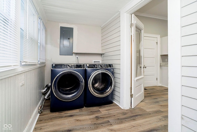 washroom with electric panel, crown molding, wooden walls, washer and dryer, and wood-type flooring