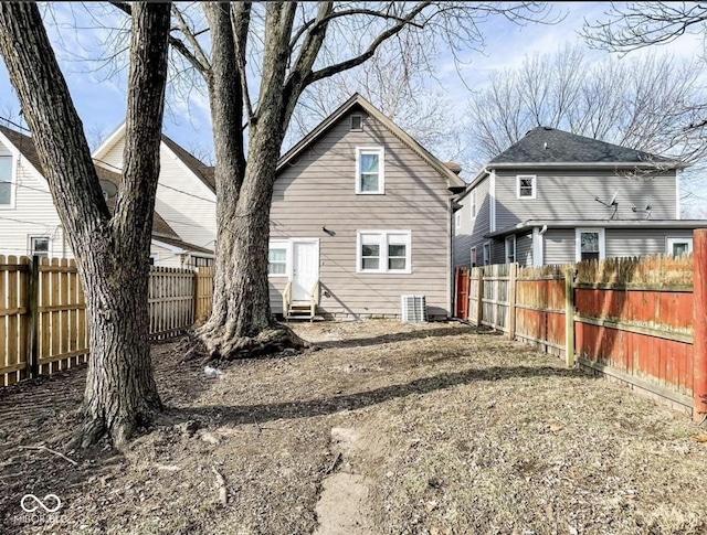 rear view of house with entry steps, a fenced backyard, and cooling unit
