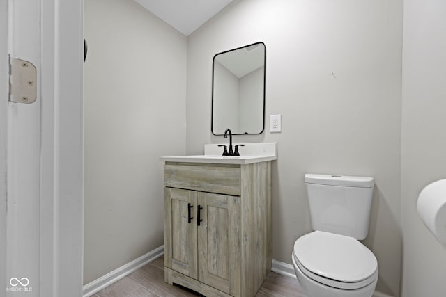 bathroom featuring vanity, wood-type flooring, vaulted ceiling, and toilet