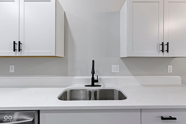 kitchen featuring white cabinets, light stone countertops, and sink