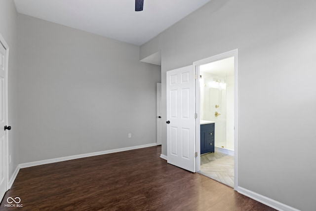 unfurnished bedroom featuring ceiling fan, dark wood-type flooring, and connected bathroom