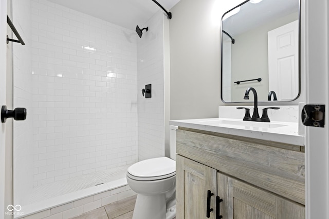 bathroom featuring a tile shower, tile patterned floors, vanity, and toilet