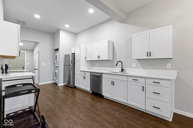 kitchen with stainless steel appliances, white cabinetry, stacked washer / drying machine, and sink