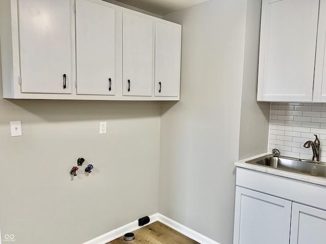 laundry room featuring sink, cabinets, and hardwood / wood-style flooring