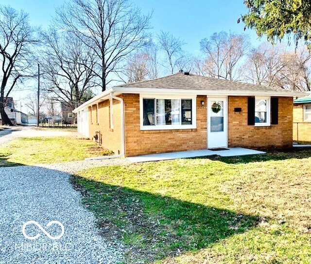 single story home featuring brick siding, driveway, and a front lawn