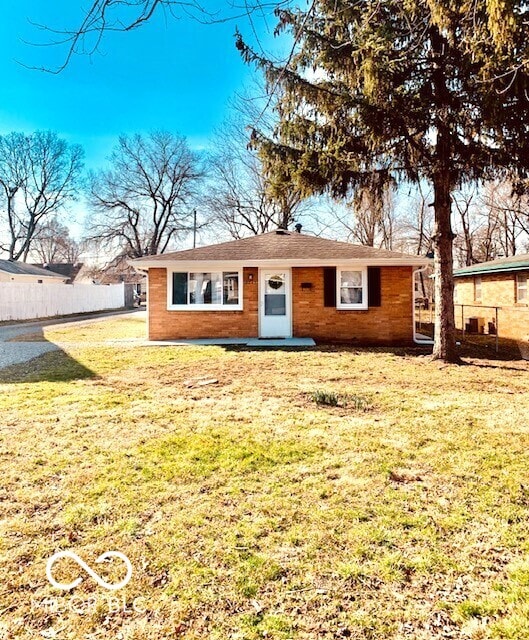 view of front of property featuring a front yard, fence, and brick siding